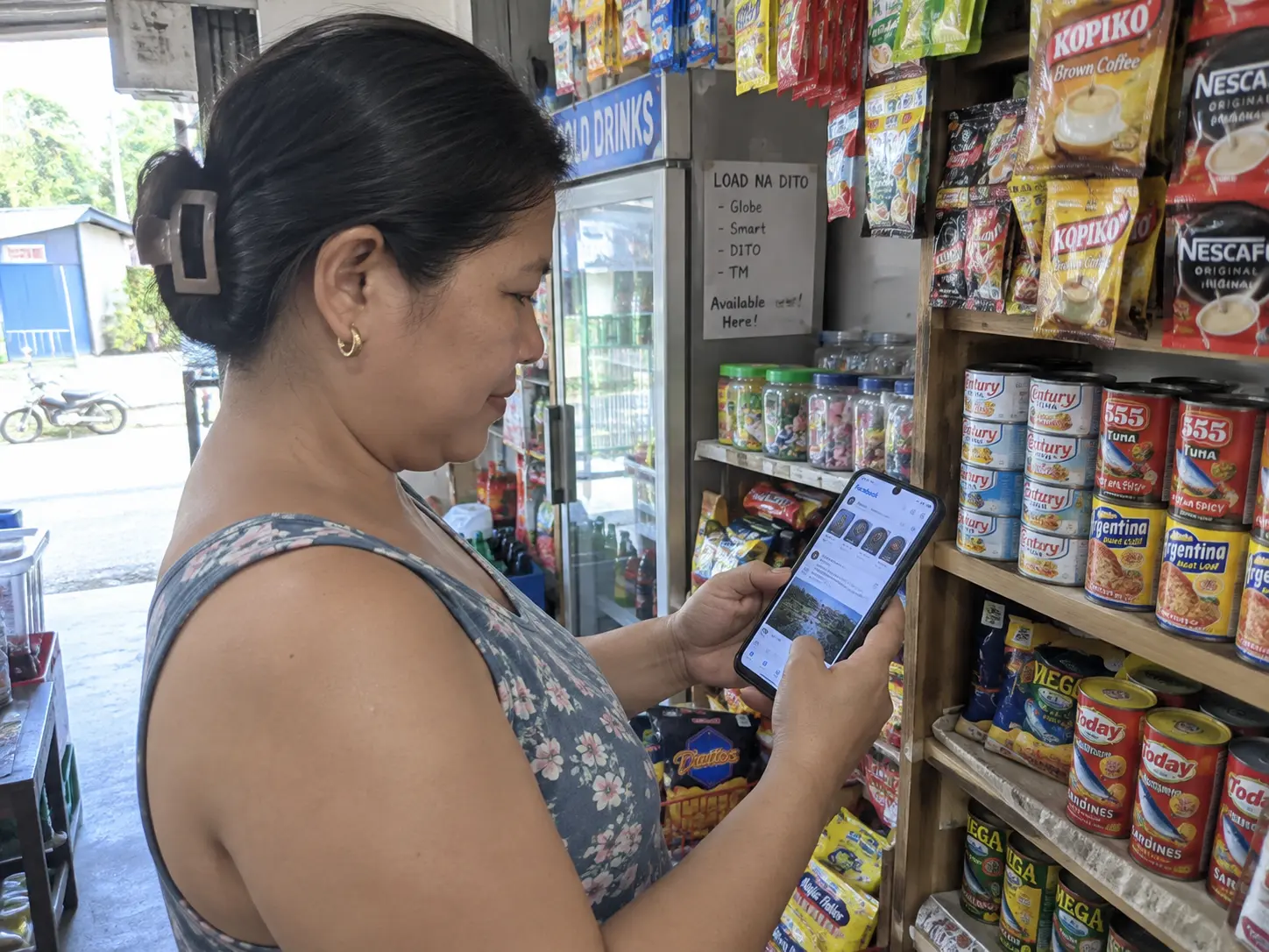 A small retail store owner checking a social media marketing app on a smartphone inside the shop